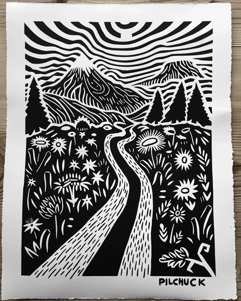 A black and white linocut print depicts a winding path leading through a landscape. The path is bordered by stylized flowers and plants, while in the background a mountain looms under a swirling sky. The print is signed "Pilchuck" in the lower right corner. The bold, simple lines create a striking visual effect.