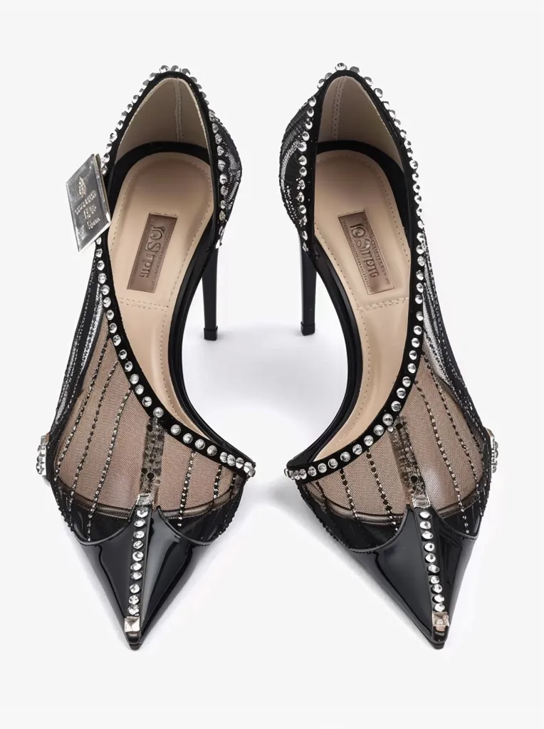 The image shows a pair of black high-heeled shoes adorned with rhinestones. The shoes have a delicate mesh upper and a pointed toe. They are a glamorous and elegant footwear option, perfect for a special occasion. The shoes are designed to elevate any outfit with their intricate details and dazzling sparkle.