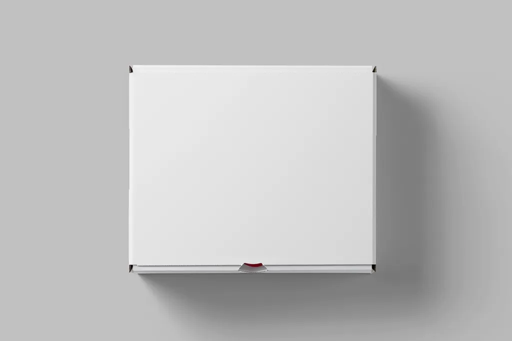 The image shows a white cardboard box, sitting on a light gray background. The box is closed and has a subtle, thin red line running along the bottom edge. There is a soft shadow underneath the box, suggesting it is slightly raised from the surface. The box is centered in the frame and fills most of the image. It appears to be a plain, unmarked box, ready for packaging or shipping.