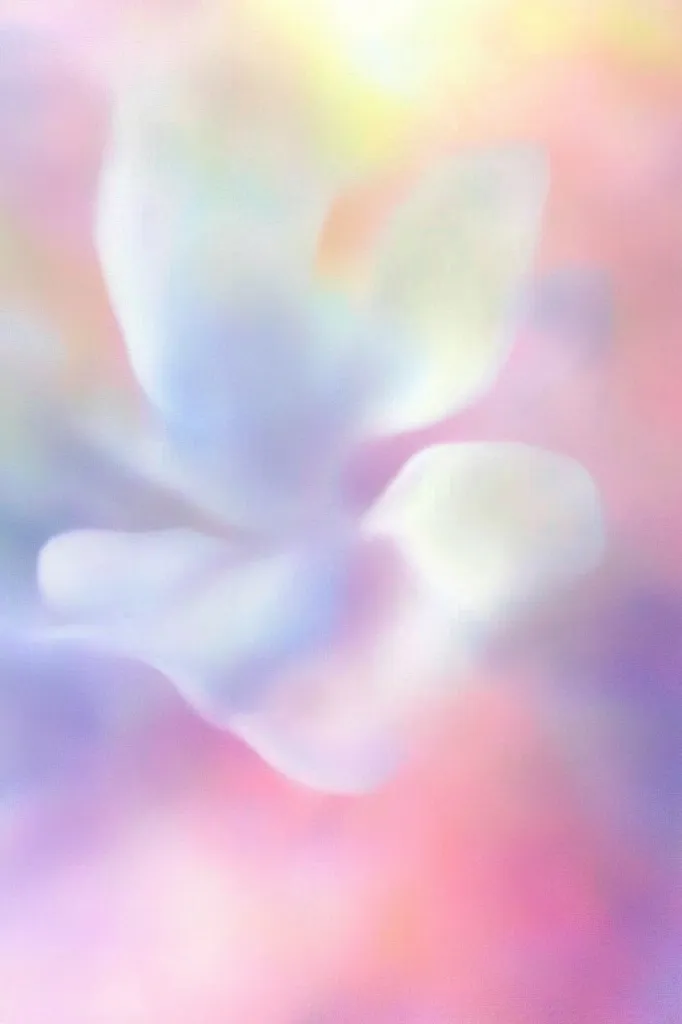 The image is a soft, dreamy blur of pastel colors. It features a hazy, ethereal shape that resembles a flower or a cloud, set against a background of gentle pink and purple hues. The overall effect is one of calmness, serenity, and a sense of light and airy beauty.