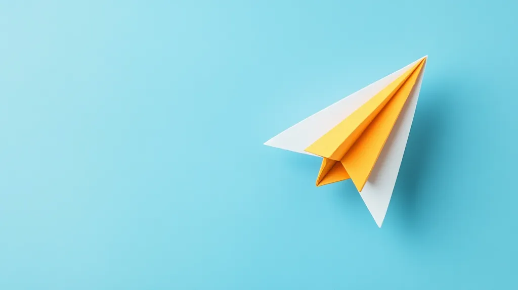 A yellow and white paper airplane sits on a light blue background. The plane is folded with the wings pointing to the right and the nose of the plane pointing to the left. The plane is in focus, while the background is slightly blurred. The image has a simple and playful feel.