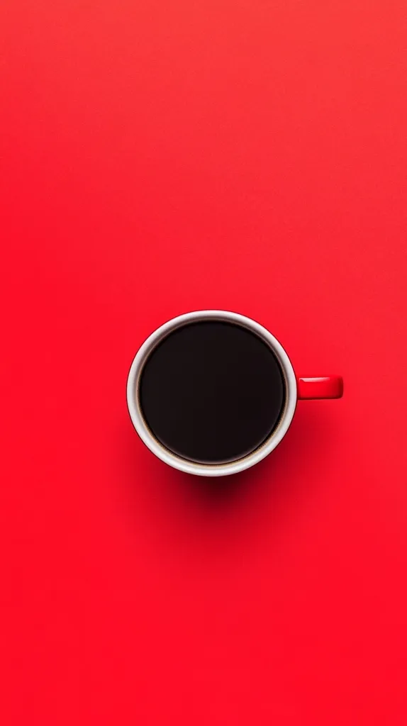 A cup of coffee sits on a bright red background. The cup is white with a red handle. The coffee is dark and fills the cup. The image is a simple and minimalist representation of a cup of coffee.
