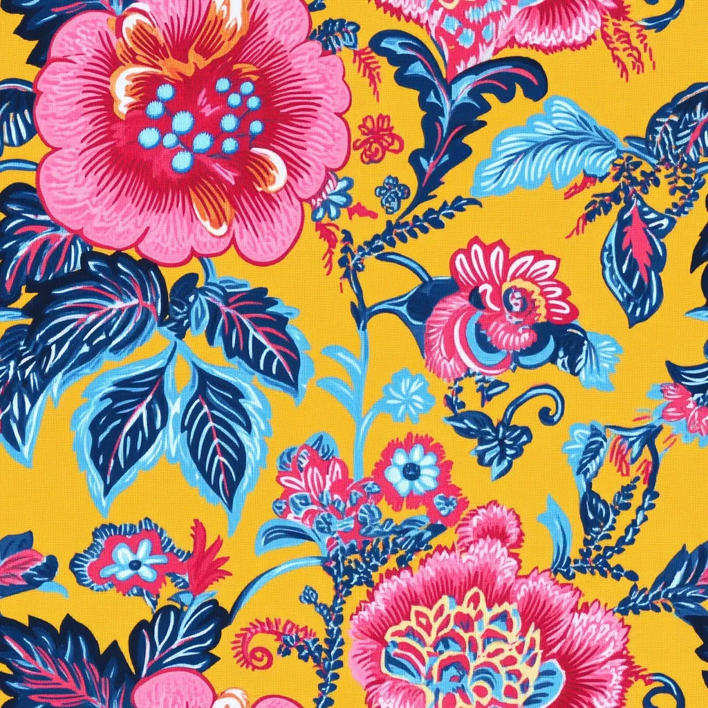 The image shows a vibrant floral textile pattern on a mustard yellow background.  Large, stylized pink and red flowers with teal centers are prominent, interspersed with smaller blossoms and intricate blue and navy foliage. The design is dense and richly colored, suggesting a bold, possibly Indian-inspired, aesthetic. The style is reminiscent of traditional paisley or chintz fabrics.  The overall effect is one of lively energy and opulent detail.