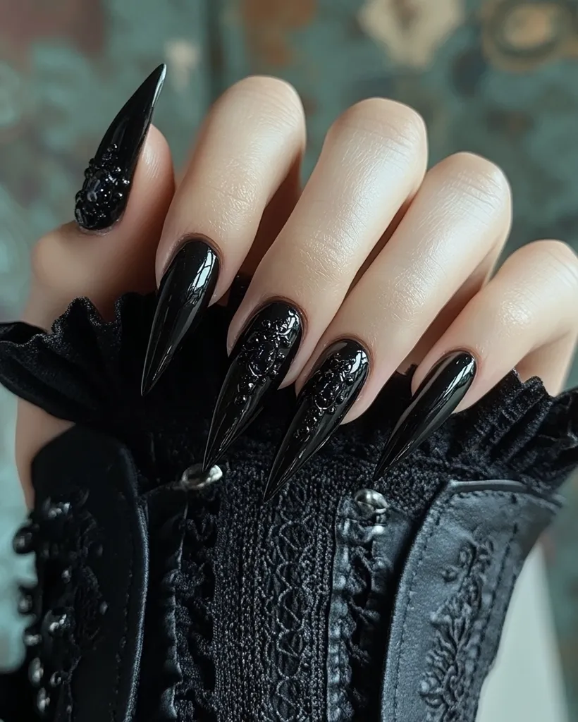 Close-up of a hand adorned with long, pointed black nails.  Several nails feature intricate black detailing resembling lace or skulls, while others are a smooth, high-gloss black. The nails are dramatically long and sharp, creating a gothic or edgy aesthetic. The hand rests on a black, lace-detailed fabric, complementing the dark nail design. The overall impression is one of elegance and darkness.