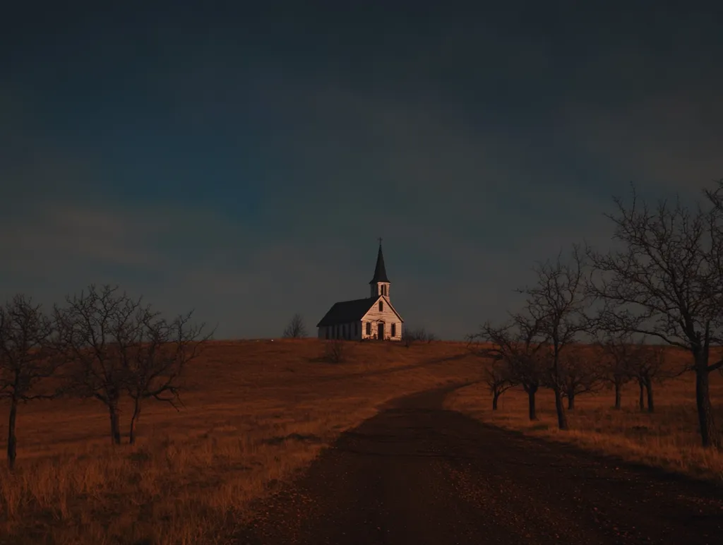 A small, white church with a steeple stands solitary atop a hill under a dark sky.  Bare, winter trees dot the surrounding landscape, their branches reaching towards the church. A dirt road winds its way from the foreground towards the hill, leading the eye directly to the isolated building. The scene evokes a sense of quiet solitude and perhaps even a touch of melancholy.