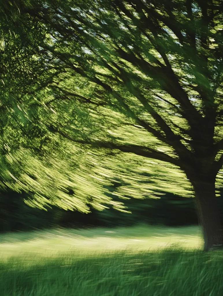 A long-exposure photograph captures the swirling motion of a tree's branches and leaves against a backdrop of a grassy field.  The vibrant green hues create a sense of energy and movement, emphasizing the dynamic interplay between the tree and the wind. The blurred effect adds an ethereal quality to the scene, transforming the natural elements into an abstract composition.