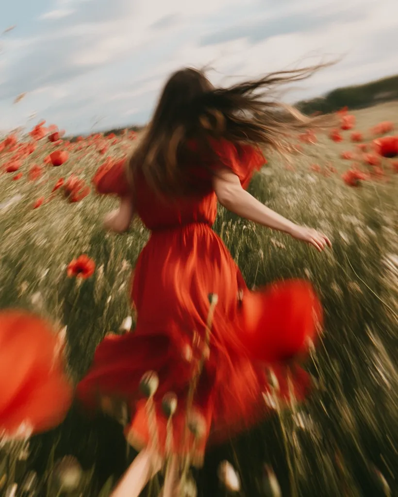 A woman in a red dress runs through a field of vibrant red poppies.  Her long hair flows behind her, blurred by motion, creating a dreamy, ethereal effect. The image is vibrant with color and movement, suggesting freedom and joy. The poppies and the dress blend together in a sea of red, emphasizing the feeling of lightness and carefree abandon.
