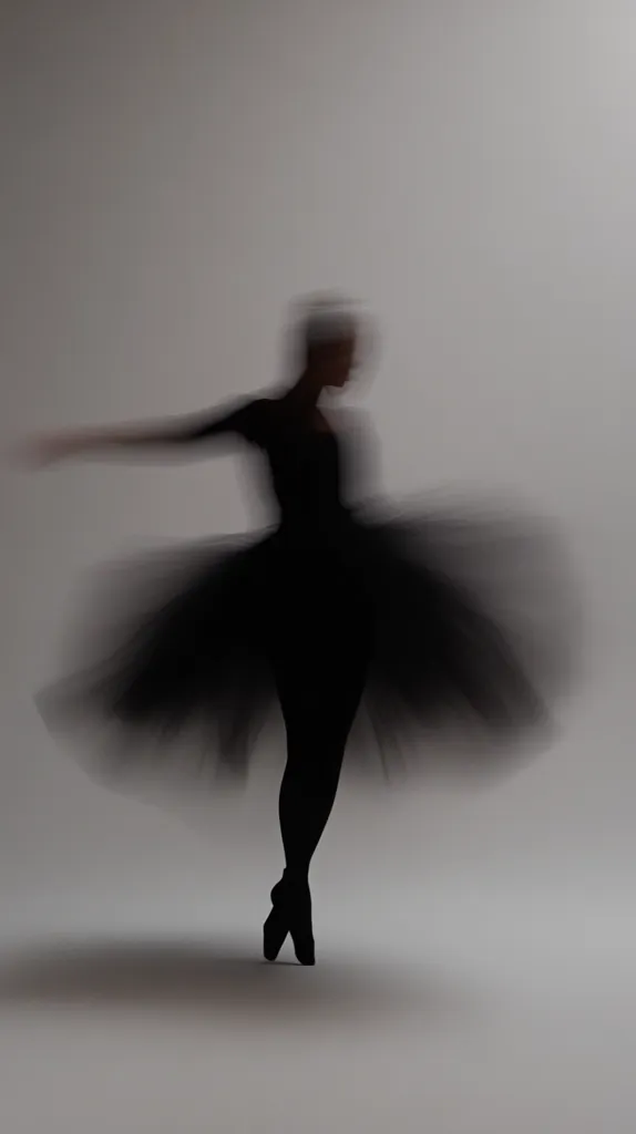 A blurred image depicts a ballerina in a black tutu, her form a silhouette against a light gray background.  The motion blur suggests a twirl or spin, emphasizing the fluidity and grace of her movement. The ballerina's posture and the delicate tulle of her costume are partially obscured by the artistic effect.  The overall mood is ethereal and elegant.