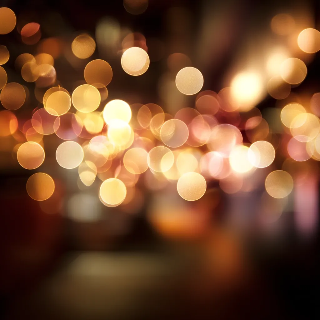 An abstract image of out-of-focus golden and amber lights.  The bokeh effect creates a warm and celebratory feel, suggesting a nighttime scene with many lights blurred into soft, glowing circles. The dark background enhances the luminosity of the lights, creating a visually appealing and festive atmosphere.