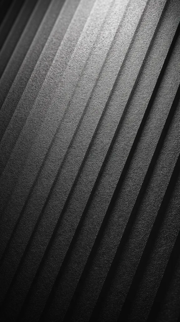 The image showcases a dark gray or black textured surface with diagonal parallel lines. The texture appears slightly grainy or rough, creating a sense of depth.  Light highlights the ridges, emphasizing the linear pattern and creating subtle variations in shade across the surface. The overall effect is one of sleek, modern minimalism.