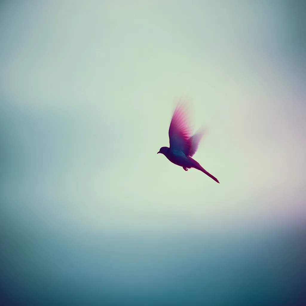A single bird soars through a soft, pastel sky.  Its wings are slightly blurred, suggesting motion and freedom.  The overall tone is serene and peaceful, evoking a sense of tranquility and effortless flight against a muted, hazy backdrop. The bird's silhouette is dark, contrasting beautifully with the light, ethereal background.