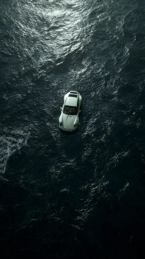 An aerial shot depicts a white Porsche 911 partially submerged in dark, choppy water.  The car floats calmly amidst the waves, its top visible above the surface. The scene is moody and atmospheric, with the dark water dominating the frame.  The contrast between the white car and the dark water is stark.