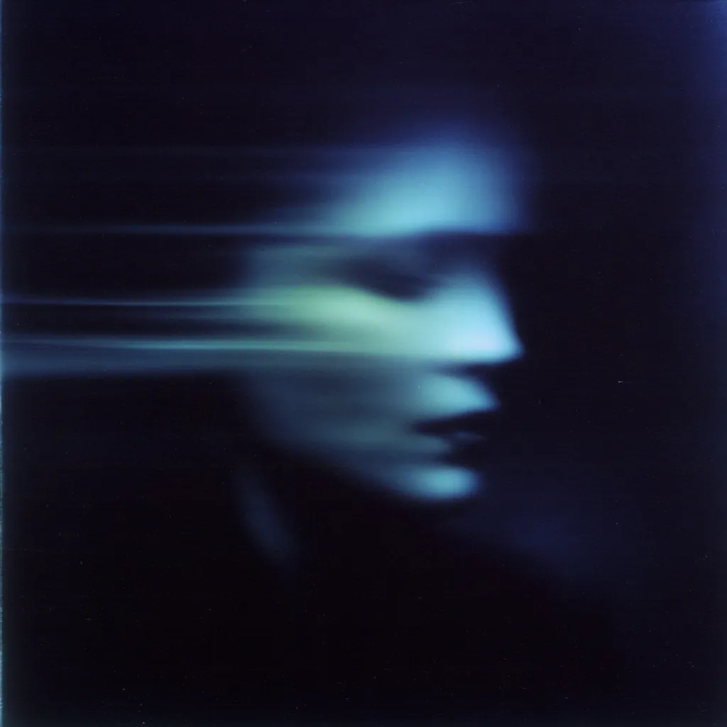 A blurred, ethereal image depicts a woman's face in profile, bathed in cool, blue light against a dark background.  The motion blur creates a sense of fleetingness and mystery, obscuring distinct features while suggesting a ghostly or dreamlike quality. The overall effect is one of haunting beauty and enigmatic emotion.