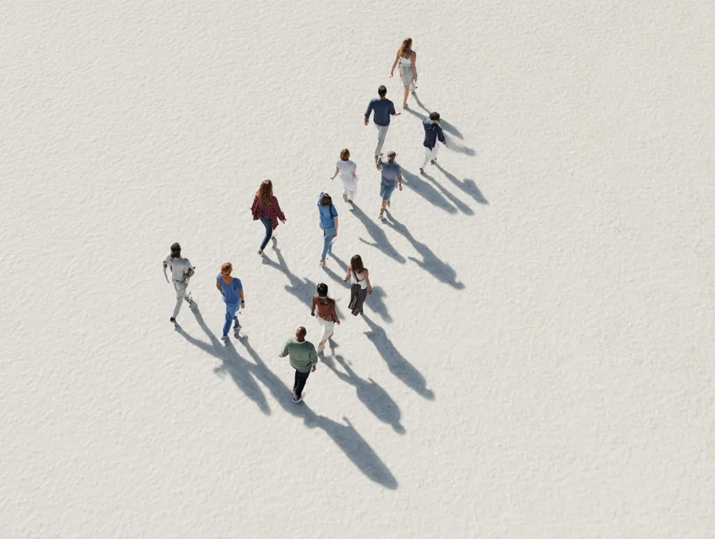 An aerial view shows a group of people walking in a diagonal line across a vast, light-colored surface.  The individuals are dressed in casual attire, and their shadows stretch behind them, creating a visually striking contrast against the plain background. The scene suggests movement and a sense of journey or shared purpose.