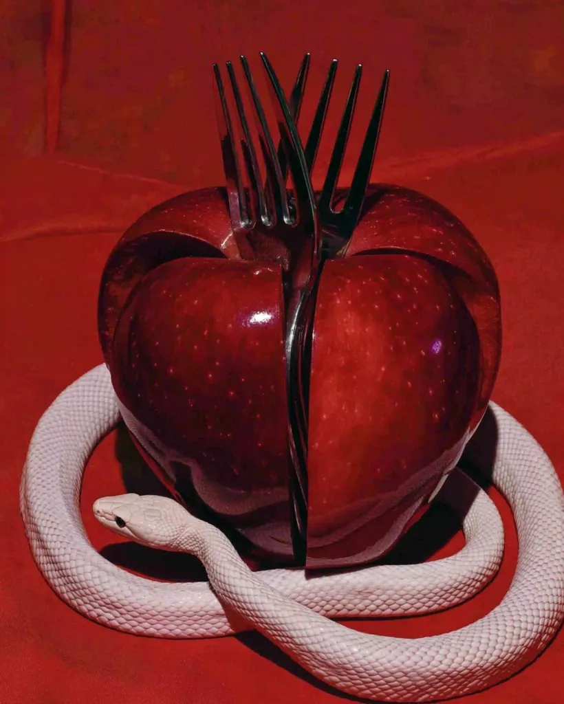 A vibrant red apple, meticulously sectioned, is pierced by several forks.  A pale snake elegantly coils around the base of the apple, creating a striking contrast against the rich red background.  The image evokes a sense of temptation and danger, reminiscent of classic allegorical imagery.