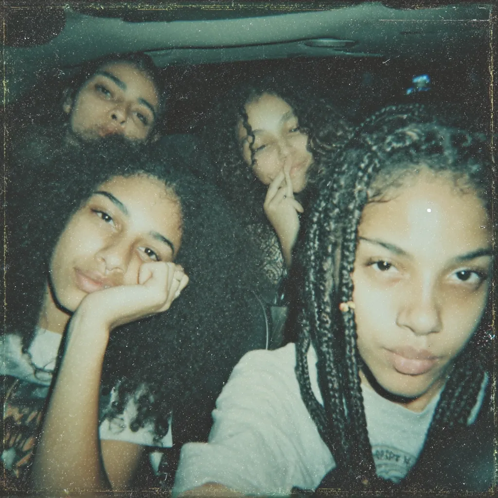 A grainy, vintage-style photograph captures four young women in a car.  The woman in the foreground, with long black braids, looks directly at the camera.  Behind her, three other women with dark curly hair are visible. The image has a nostalgic, slightly out-of-focus quality, suggestive of a candid moment. The overall mood is relaxed and intimate.