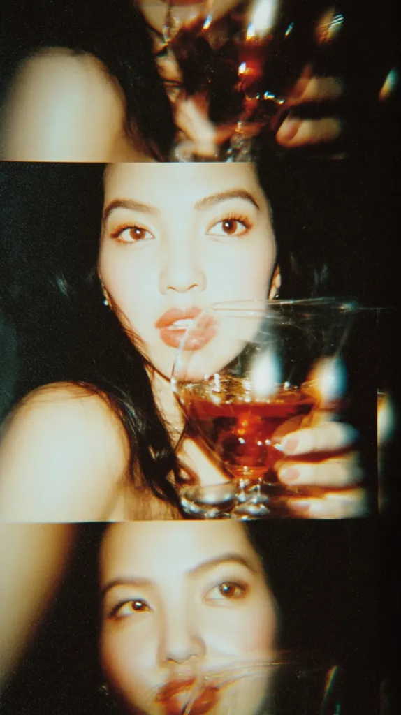 A triptych of film-like photos features a woman with dark hair and striking makeup.  She holds and drinks from a glass of amber liquid in each frame.  The images have a vintage, slightly blurry aesthetic, suggesting a nighttime setting. The overall mood is sultry and glamorous.